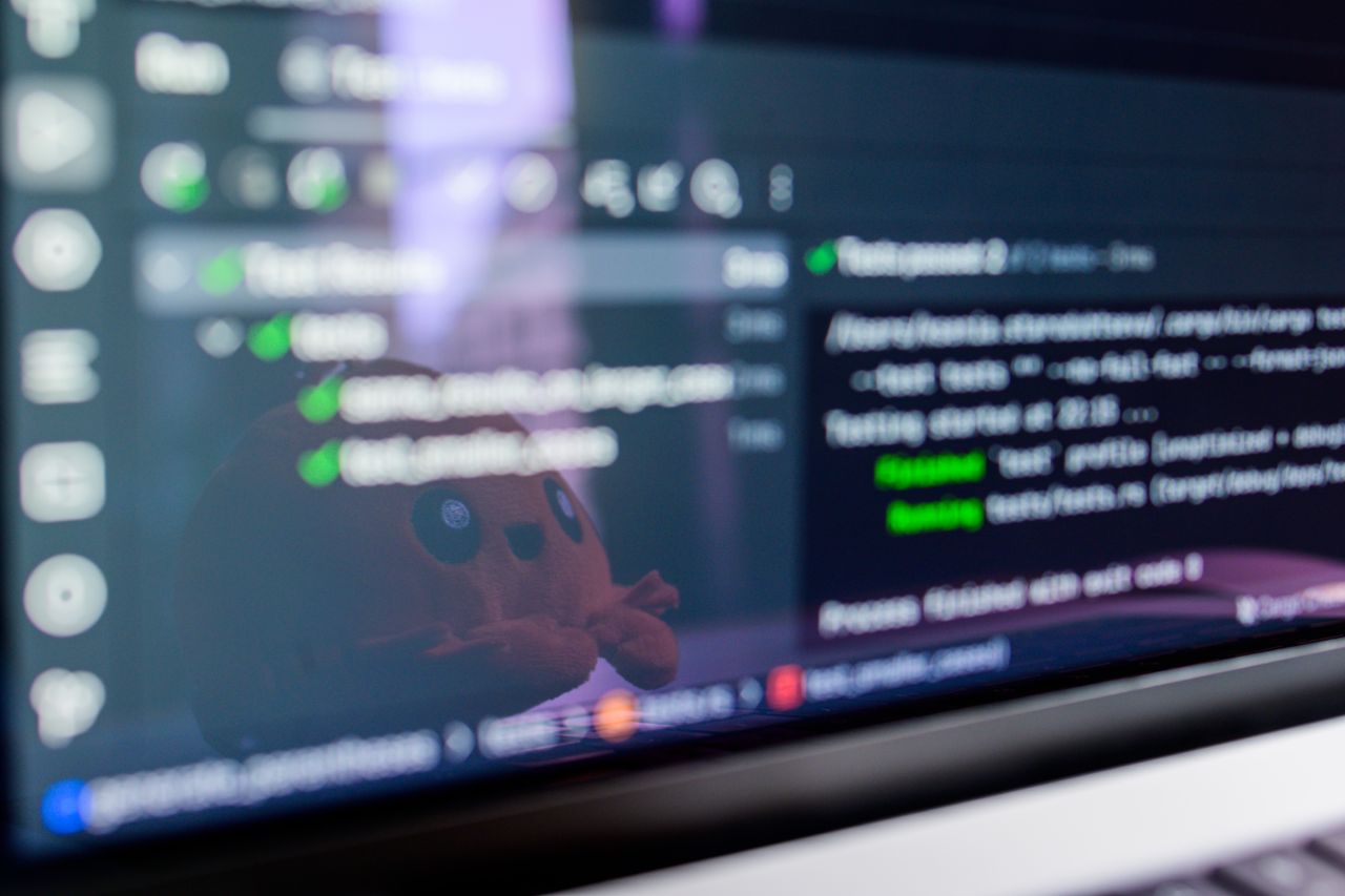 Home Close-up of a laptop screen displaying programming code with a cute plush toy reflecting.